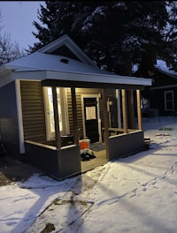 a small house with a porch and snow on the ground