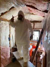 a man in a white suit standing in a room with insulation