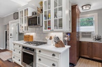 a kitchen with white cabinets and wood floors