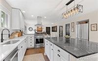 a kitchen with white cabinets and marble counter tops