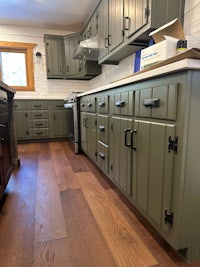 a kitchen with green cabinets and wood floors
