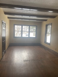 an empty room with hardwood floors and windows
